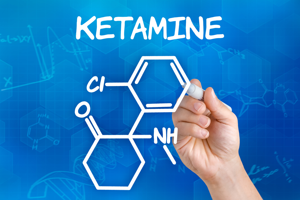 Ketamine chemical compound illustrated in white marker on a blue background.